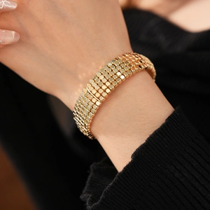 Gros plan d'un bracelet manchette doré multi-rangs sur poignet contre tricot noir