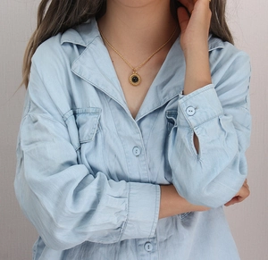 Détail d'un collier plaqué or 18 carats avec pendentif en agate noire porté par un mannequin