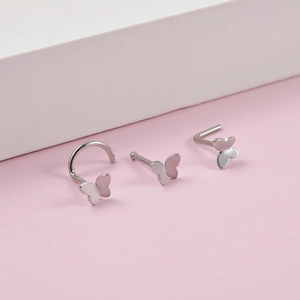 Detail of silver butterfly nose rings featuring hook, bone, and L-shape stud designs