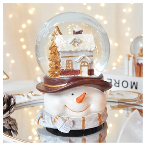 Detailed view of snowman snow globe with cabin and golden Christmas tree inside