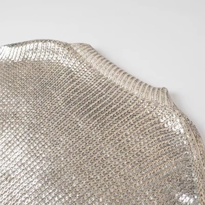 Detail of silver metallic knit sweater showing wood ear trim and ruffled shoulder texture