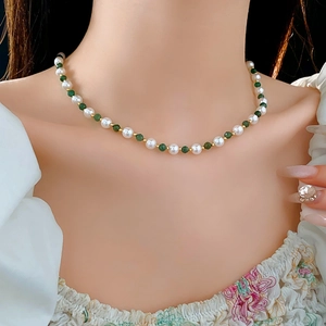 Detail of beaded necklace with white pearls, green faceted beads and gold spacers
