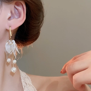 Detailed close-up of acrylic flower earrings with pearl tassels on a model ear