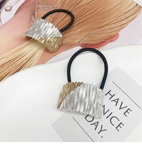 Macro detail of alloy arch hair ties with gold and silver wave textures on black elastic bands