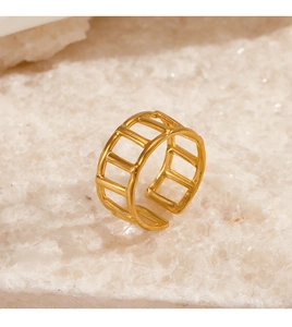 Detail view of gold geometric hollow open ring displayed on white mineral stone base