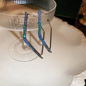 Detailed view of geometric earrings with blue-green gradient rhinestones on ceramic