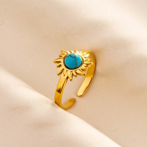 Macro detail of sun-shaped gold ring with blue turquoise stone on textured fabric