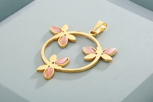 Nahaufnahme des goldenen Libellen-Anhängers mit rosa Katzenaugenstein auf Display