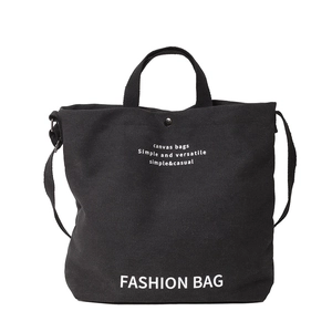 Black canvas tote bag with double handles and white lettering in a minimalist design
