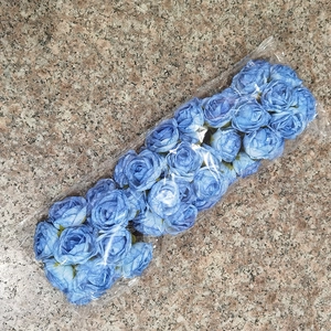 Detailed view of sky blue artificial rose flower heads in clear plastic bag packaging