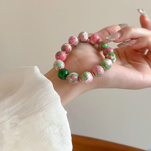 Detail of beaded bracelet with pink floral ceramic beads and gold-plated metal spacers