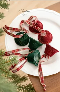 Red and green flocked Christmas bells with gold glitter and checkered ribbons on pine branches