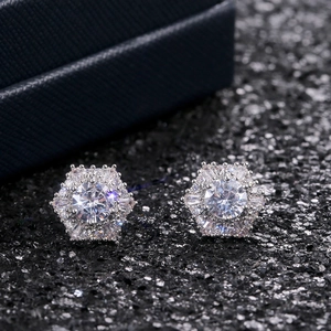 Macro shot of silver hexagonal snowflake studs with sparkling zircon stones on black background