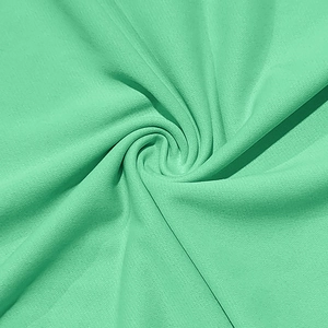 Detailed texture of mint green knit fabric with elegant draping and spiral fold patterns