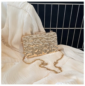 Detail of metallic acrylic evening clutch with gold foil water ripples and metal chain