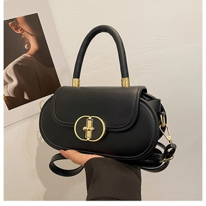 Dettaglio di borsa nera ovale con fibbia dorata e tracolla sottile in pelle sintetica