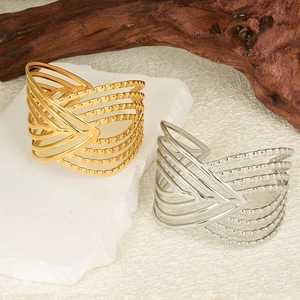 Detailed macro view of gold and silver cutout V-shaped open bangles on a stone base