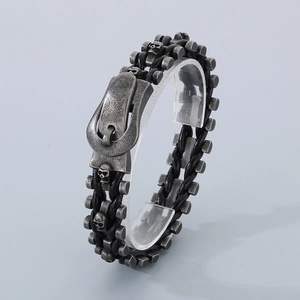 Detail of silver skull and bike chain design on black braided leather punk bracelet