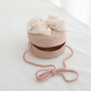 Détail d'un sac en paille rose avec nœud en dentelle beige et petites fleurs décoratives