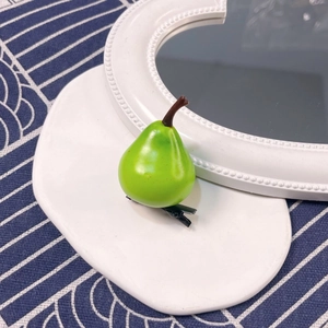 Macro view of a realistic green pear hair clip with a durable black duckbill metal clamp