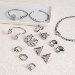 Minimalist silver stainless steel jewelry set with bracelets, rings, and earrings on display