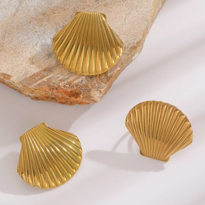 Detailed close-up of golden shell jewelry set with earrings and ring on natural rock