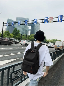 Man wearing a minimalist black canvas backpack with leather details on city street