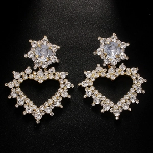 Vue macro des boucles d'oreilles clips cœur dorées avec strass brillants sur fond noir
