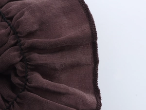 Macro detail of brown knitted fabric with ruffle edge and black overlock stitching