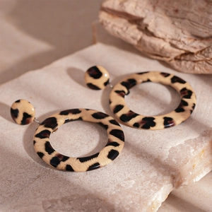 Close-up of leopard print resin hoop earrings on a natural stone surface