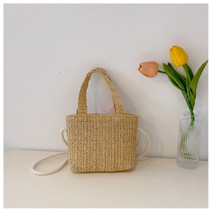 Chic beige straw woven crossbody bag for kids displayed next to a vase of tulips