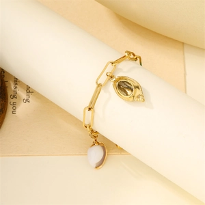 Close-up of golden shell and white bead charms on a minimalist stainless steel chain