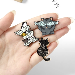 Three cute enamel cat pins featuring coffee and fish themes held in hand for scale