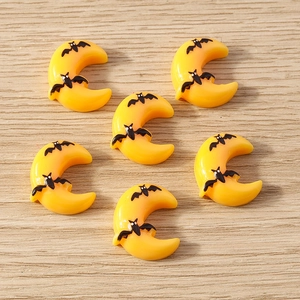 Flat lay of yellow crescent moon resin charms with black bats for Halloween DIY crafts