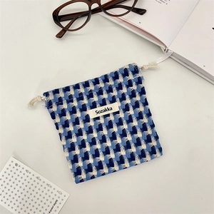 Détail d'un sac à cordon en tricot à damier bleu avec étiquette tissée sur fond plat