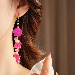 Détail de boucles d'oreilles fleurs roses avec perles et métal doré sur un mannequin