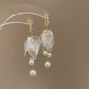 Detailed view of acrylic flower petal earrings with pearl tassels and gold accents