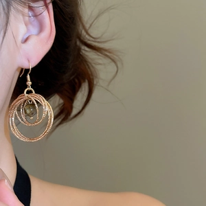 Close-up of elegant gold layered circular earrings with tiger eye stone on model