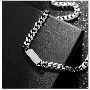 Detailed view of silver Cuban chain with smooth rectangular plaque on black textured box