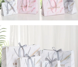 Macro detail of white and pink marble gift bags with gold foil SWEET TIMES text