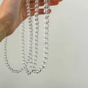 Close-up of hand-held transparent crystal glass beaded necklace with high light refraction