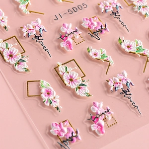 Macro view of 5D embossed nail stickers featuring pink camellias and golden line details