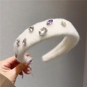 Detail of white plush headband featuring colorful gemstones and a heart LOVE pendant chain