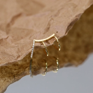 Detailed close-up of a three-tier gold ear cuff with small sparkling crystals on paper