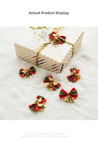 Detail of red and green plaid Christmas bows with golden bells on white snow surface