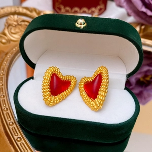 Close-up of vintage heart stud earrings with red gemstones in a green velvet jewelry box