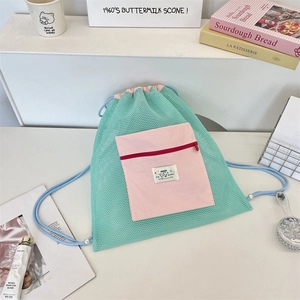 Détail du sac à dos en maille vert menthe avec poche rose zippée et détails de perles
