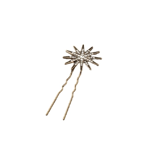 Détail d'une épingle à cheveux étoile dorée avec strass scintillants et design ondulé