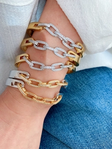 Close-up of elegant gold and silver C-shape bracelets with cubic zirconia on model