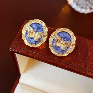 Detailed macro view of vintage round earrings with gold butterfly on blue enamel